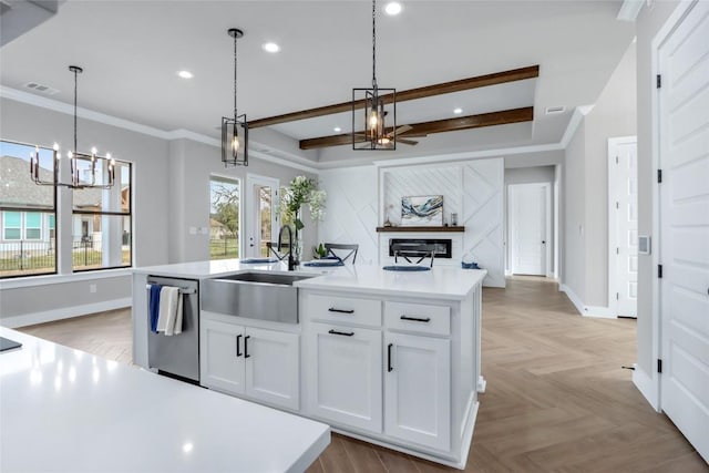 kitchen featuring light countertops, stainless steel dishwasher, white cabinetry, and a center island with sink