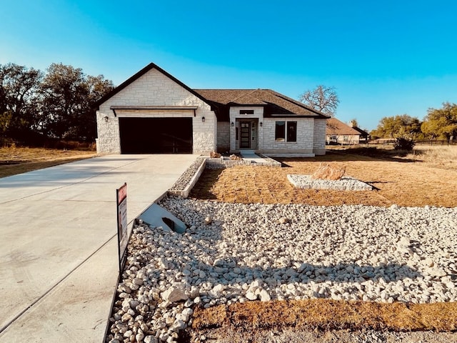 view of front of property with an attached garage, driveway, and stone siding