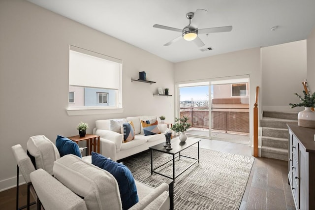 living room featuring visible vents, baseboards, a ceiling fan, stairway, and wood finished floors