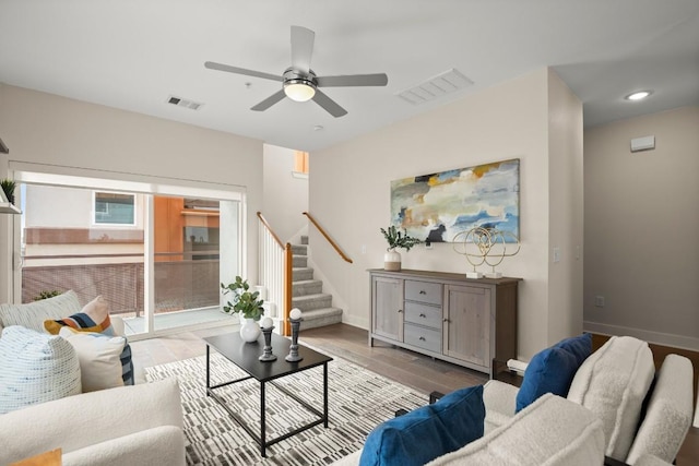 living room featuring wood finished floors, visible vents, baseboards, and stairs