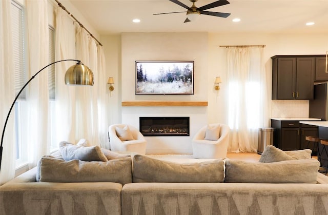 living room featuring ceiling fan, a glass covered fireplace, and recessed lighting