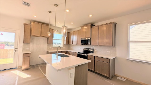 kitchen featuring visible vents, an island with sink, a sink, stainless steel appliances, and decorative backsplash