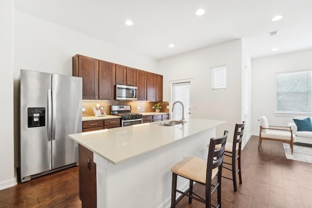 8901 Parker Ranch Cir Unit A, Austin, TX 78748 - kitchen featuring appliances with stainless steel finishes, a breakfast bar, a sink, light countertops, and dark wood-style floors