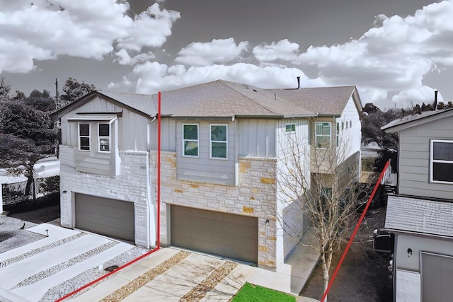 view of front of home featuring an attached garage, stone siding, a shingled roof, and board and batten siding