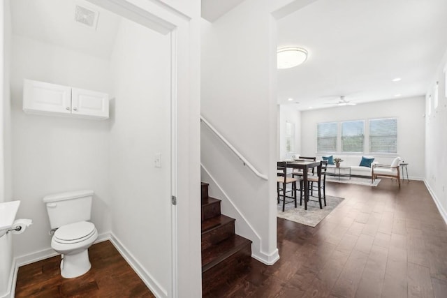 staircase with a ceiling fan, wood finished floors, visible vents, and baseboards