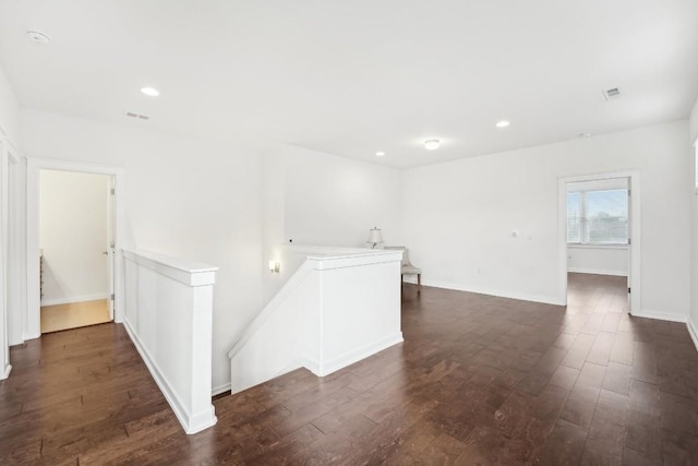 empty room with dark wood-style floors, baseboards, visible vents, and recessed lighting