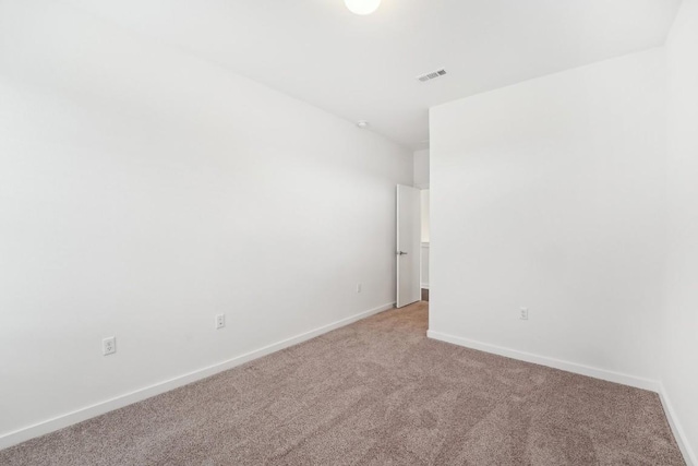 spare room with baseboards, visible vents, and light colored carpet