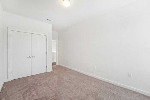 unfurnished bedroom with a closet, carpet flooring, visible vents, and baseboards