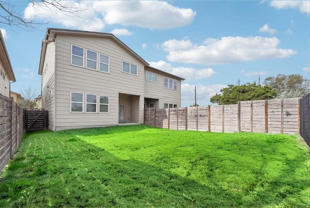 rear view of house with a fenced backyard and a lawn