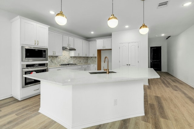 kitchen featuring a large island with sink, pendant lighting, white cabinetry, and stainless steel appliances