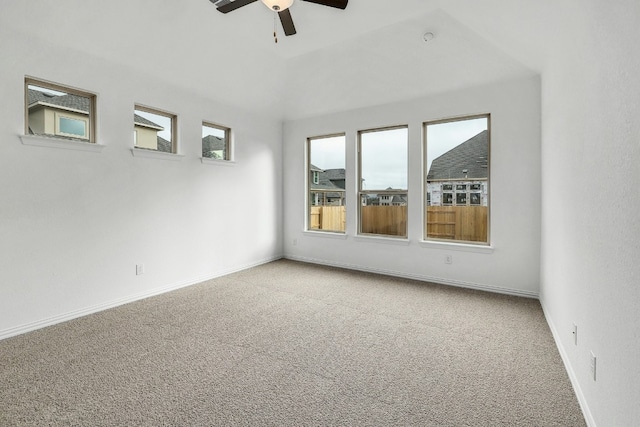 empty room with carpet flooring, baseboards, ceiling fan, and vaulted ceiling