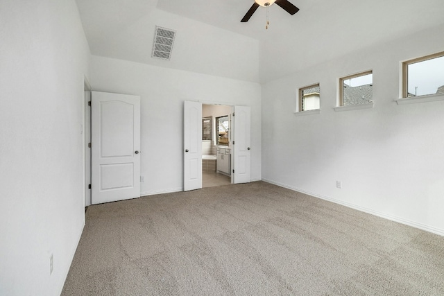 unfurnished bedroom featuring ensuite bath, carpet flooring, baseboards, visible vents, and vaulted ceiling