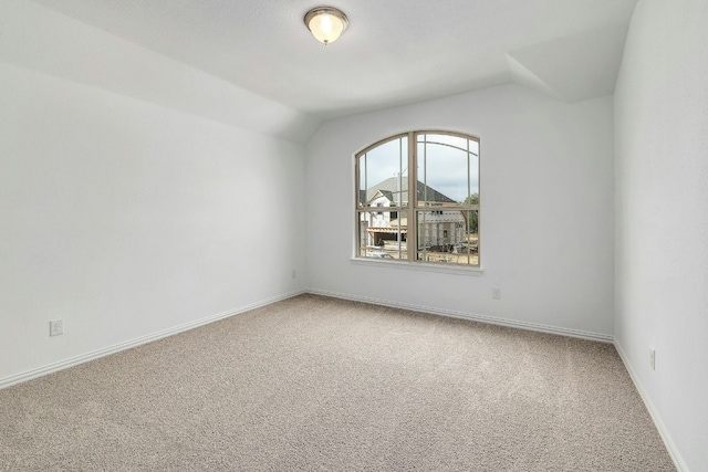 carpeted empty room featuring baseboards and lofted ceiling