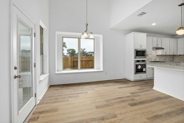 kitchen featuring light countertops, pendant lighting, white cabinets, and appliances with stainless steel finishes