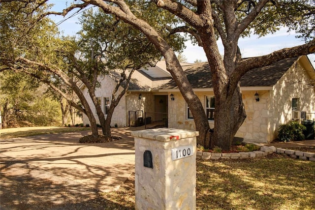 view of front of home with stone siding and roof with shingles