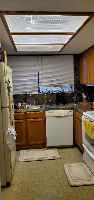 kitchen with dark countertops, light floors, brown cabinets, and white appliances