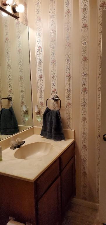 bathroom featuring vanity and wallpapered walls