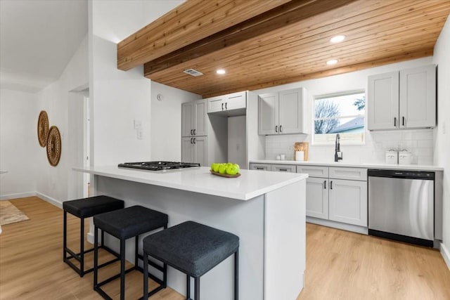 kitchen with light countertops, appliances with stainless steel finishes, a breakfast bar, and light wood-style floors