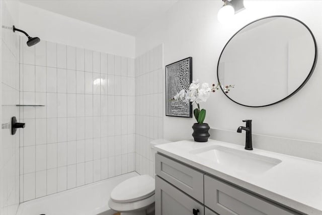 full bathroom featuring toilet, tiled shower, and vanity