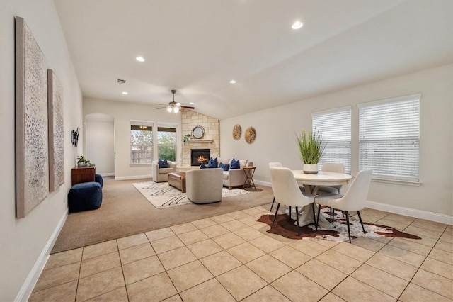 3541 Guadalajara St, Round Rock, TX 78665 - dining room featuring a fireplace, light tile patterned floors, arched walkways, light colored carpet, and a ceiling fan