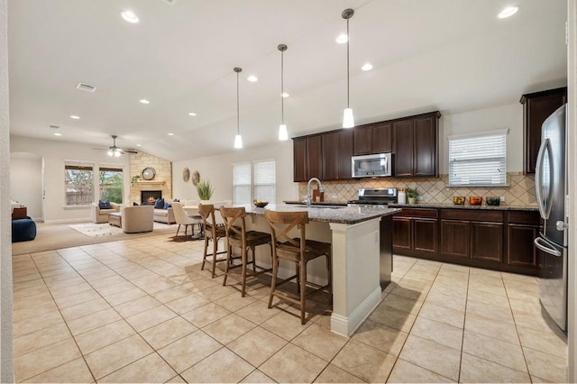3541 Guadalajara St, Round Rock, TX 78665 - kitchen with appliances with stainless steel finishes, light tile patterned flooring, a fireplace, open floor plan, and backsplash