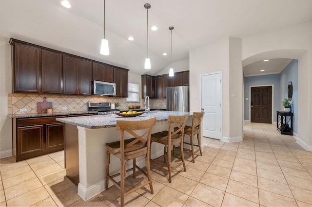 3541 Guadalajara St, Round Rock, TX 78665 - kitchen with appliances with stainless steel finishes, arched walkways, backsplash, light tile patterned flooring, and dark brown cabinets
