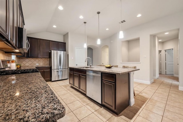 3541 Guadalajara St, Round Rock, TX 78665 - kitchen featuring appliances with stainless steel finishes, dark brown cabinetry, backsplash, arched walkways, and dark stone counters