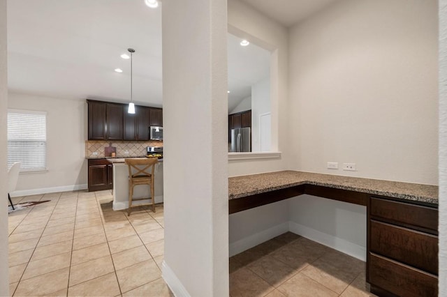 3541 Guadalajara St, Round Rock, TX 78665 - kitchen with built in desk, appliances with stainless steel finishes, light tile patterned floors, dark brown cabinetry, and recessed lighting