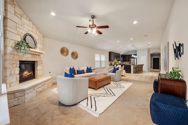 living area with a ceiling fan, light colored carpet, vaulted ceiling, a stone fireplace, and recessed lighting