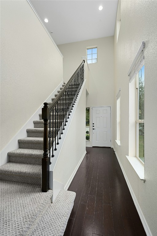 entrance foyer featuring baseboards, a towering ceiling, dark wood-type flooring, stairs, and recessed lighting