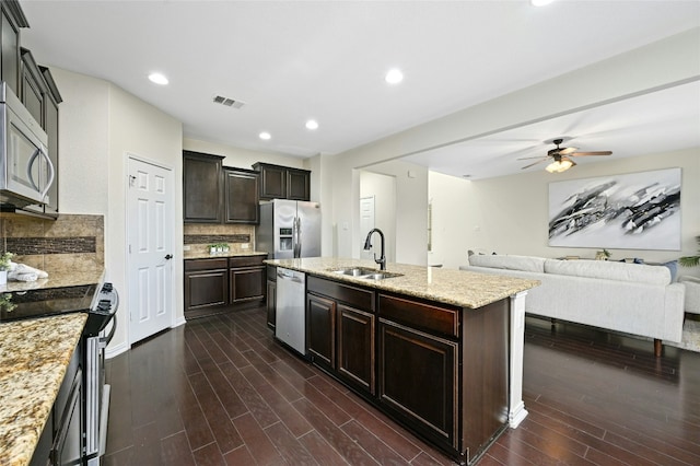 kitchen with a sink, visible vents, open floor plan, appliances with stainless steel finishes, and a center island with sink