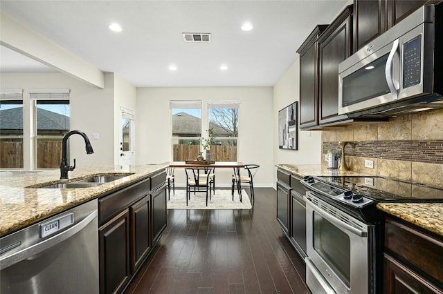 kitchen featuring tasteful backsplash, visible vents, dark wood-style flooring, stainless steel appliances, and a sink