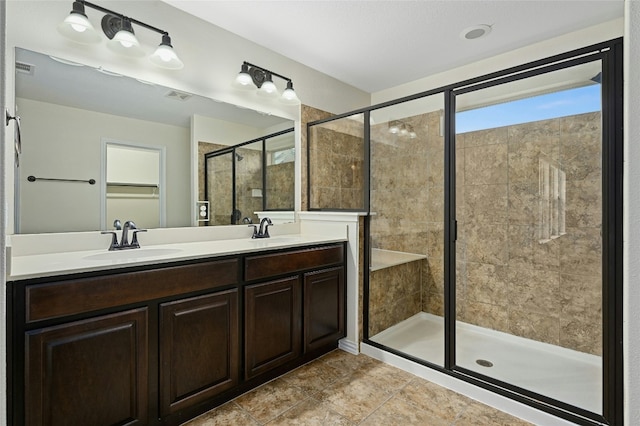 bathroom featuring double vanity, a stall shower, a sink, and visible vents