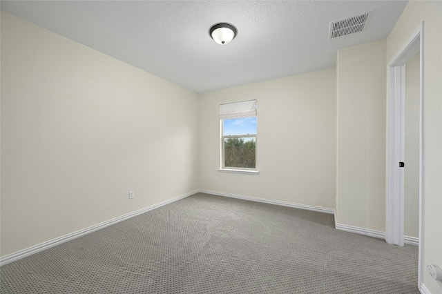 carpeted spare room featuring baseboards, visible vents, and a textured ceiling