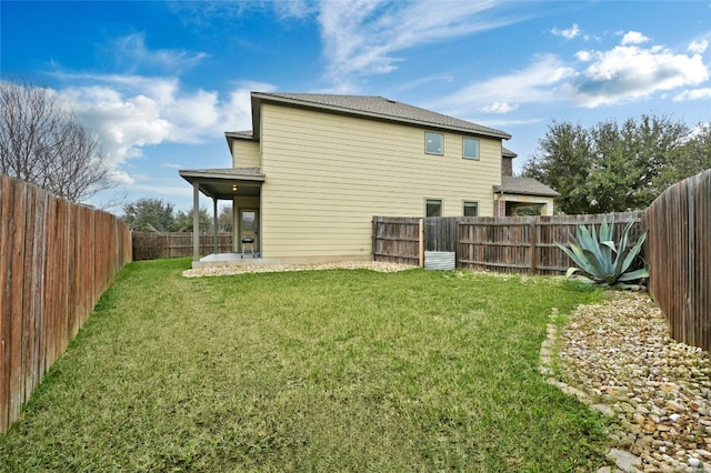 rear view of house featuring a patio area, a fenced backyard, and a lawn