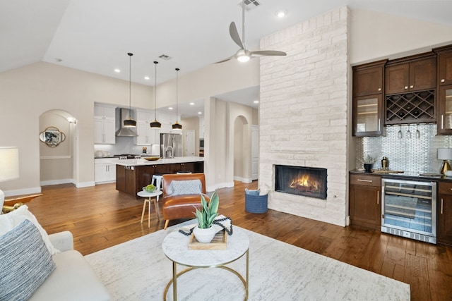 living room featuring beverage cooler, arched walkways, vaulted ceiling, and dark wood-type flooring