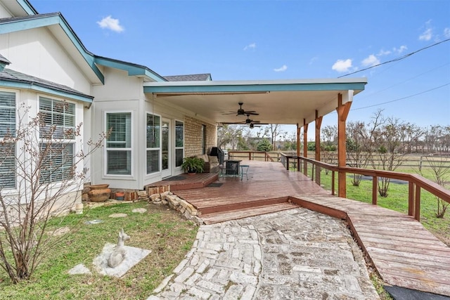 deck featuring a ceiling fan, outdoor dining space, a yard, and fence