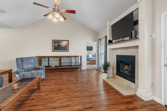 living room featuring a ceiling fan, a fireplace, baseboards, and wood finished floors