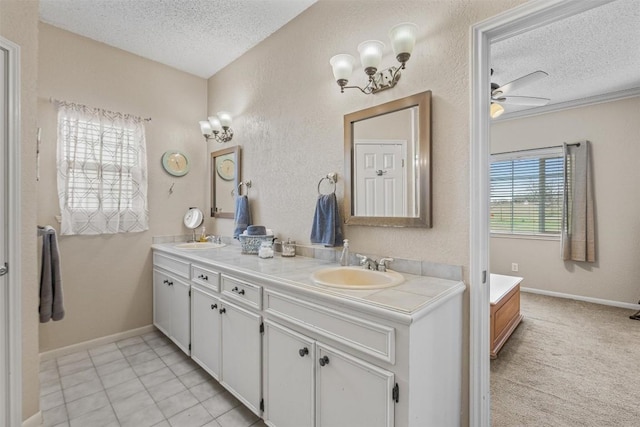 bathroom featuring a textured ceiling, double vanity, a sink, and a ceiling fan