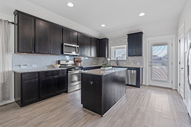 kitchen featuring stainless steel appliances, a sink, decorative backsplash, light wood-style flooring, and recessed lighting