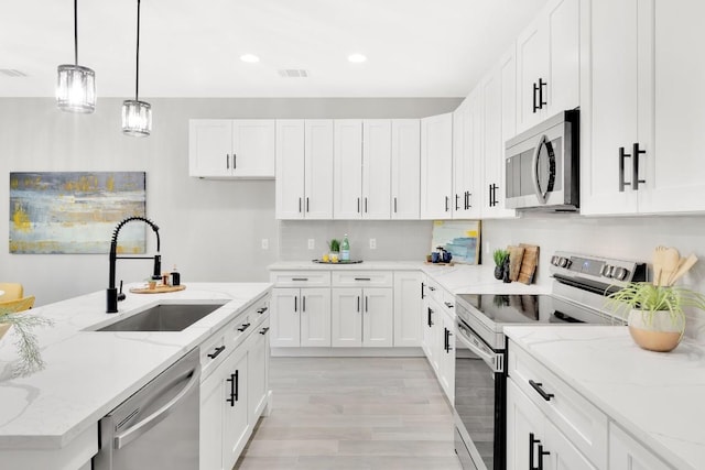 137 Puu Waa Waa Ln, Bastrop, TX 78602 - kitchen with appliances with stainless steel finishes, white cabinetry, light wood finished floors, light stone countertops, and recessed lighting