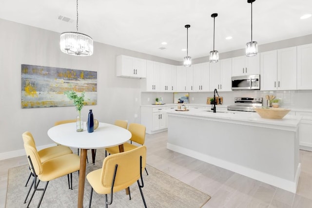 137 Puu Waa Waa Ln, Bastrop, TX 78602 - kitchen with stainless steel appliances, light countertops, white cabinets, an island with sink, and recessed lighting