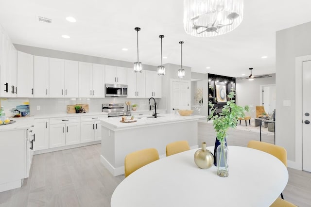 137 Puu Waa Waa Ln, Bastrop, TX 78602 - kitchen with stainless steel appliances, a kitchen island with sink, light countertops, light wood-type flooring, and tasteful backsplash