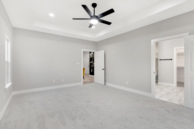 137 Puu Waa Waa Ln, Bastrop, TX 78602 - unfurnished bedroom with a spacious closet, a raised ceiling, light carpet, recessed lighting, and ceiling fan