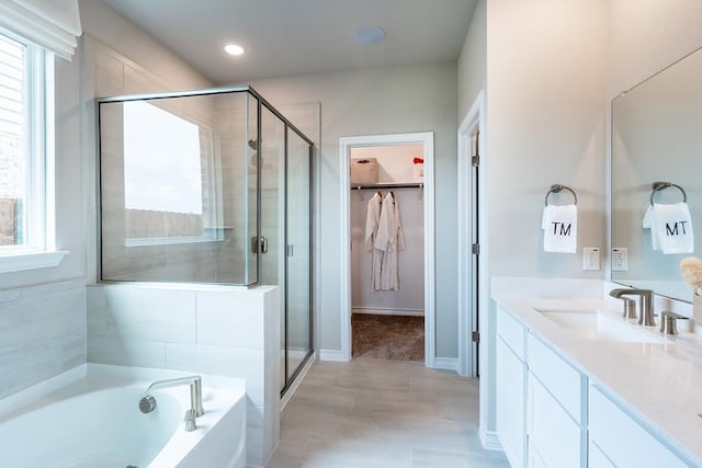 full bath featuring a walk in closet, a garden tub, plenty of natural light, and vanity