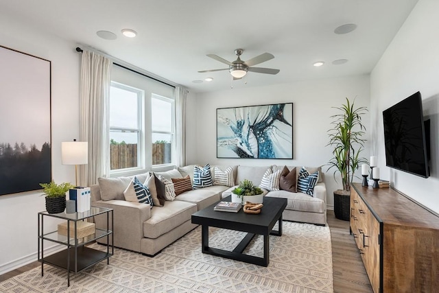 living room featuring light wood finished floors, a ceiling fan, and recessed lighting