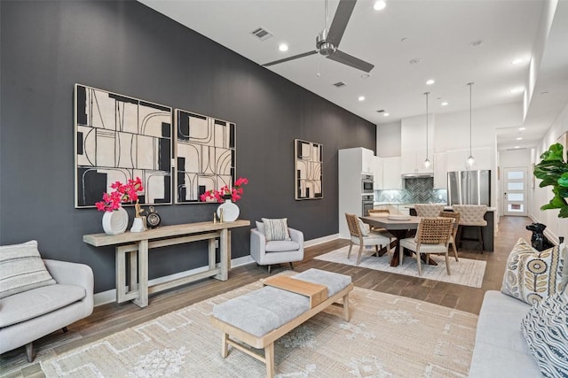 living room with a towering ceiling, light wood finished floors, baseboards, and visible vents