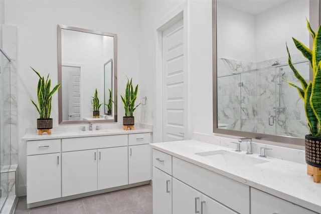 full bath with tile patterned flooring, a marble finish shower, two vanities, and a sink