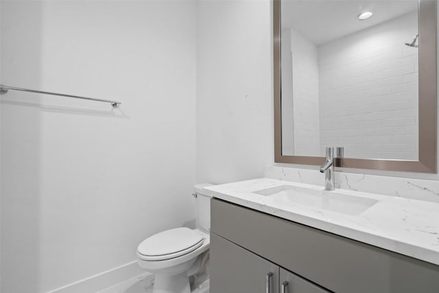 bathroom with baseboards, vanity, and toilet