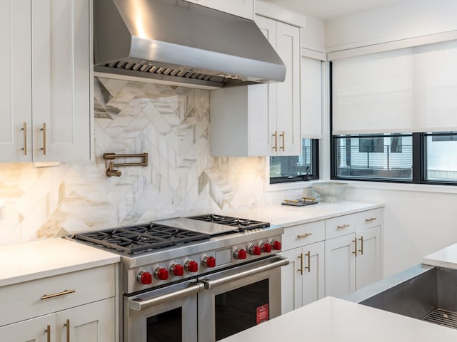 kitchen featuring range with two ovens, white cabinets, light countertops, and wall chimney exhaust hood